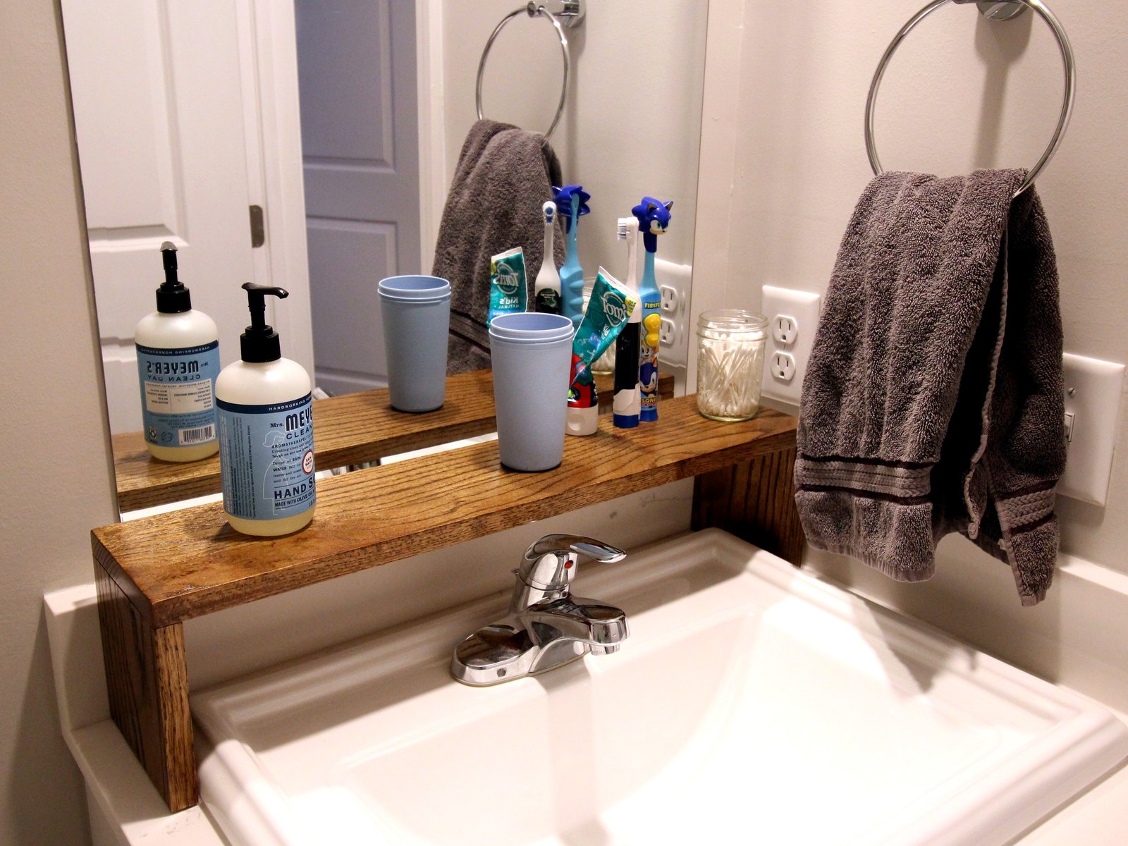 Custom oak shelf built over a bathroom sink, spanning the width of the mirror